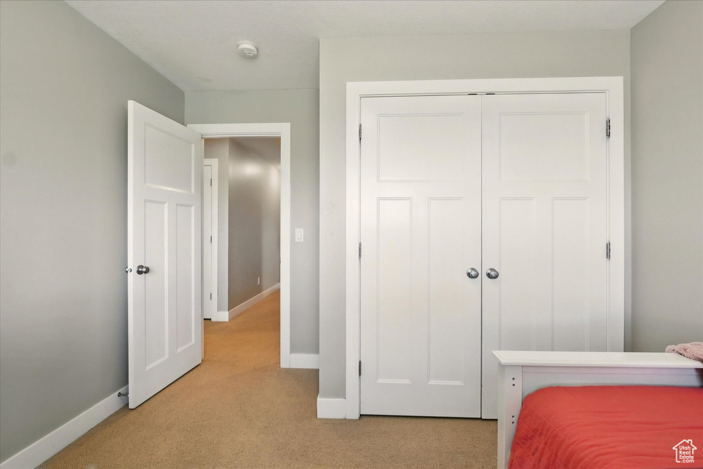 Bedroom with light carpet, baseboards, and a closet