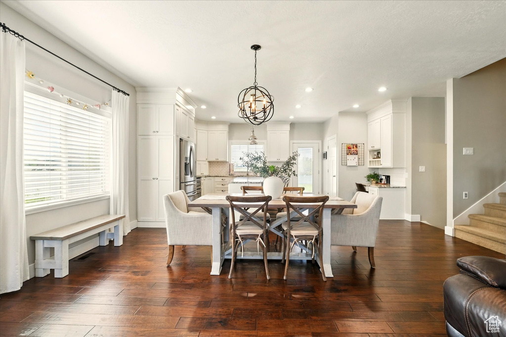 Dining area with a chandelier, recessed lighting, dark wood-style flooring, stairway, and baseboards