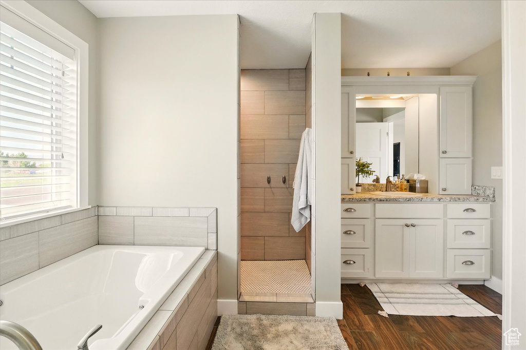 Bathroom with a garden tub, vanity, wood finished floors, and a stall shower