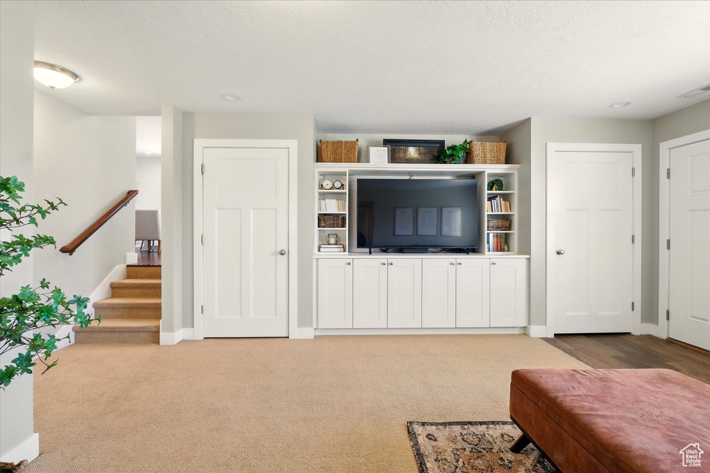 Living room with baseboards, light carpet, and stairway