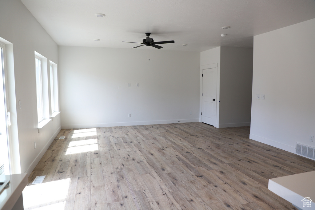 Unfurnished room featuring light wood-style floors, a ceiling fan, and baseboards