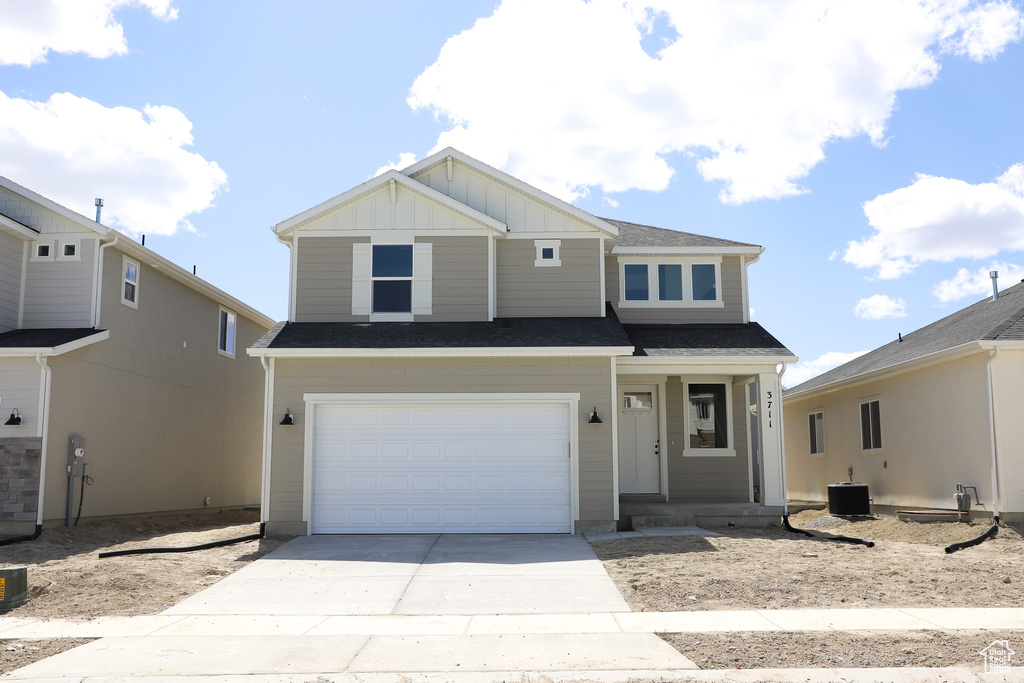 View of front facade featuring central air condition unit, board and batten siding, concrete driveway, an attached garage, and a shingled roof