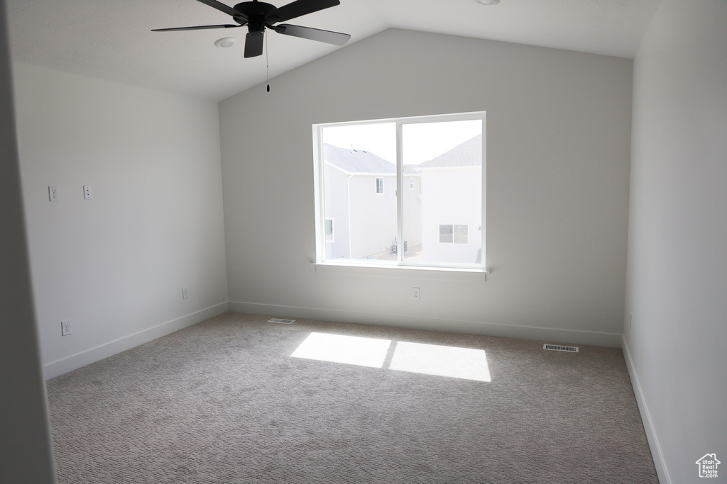 Spare room featuring carpet, ceiling fan, lofted ceiling, and baseboards