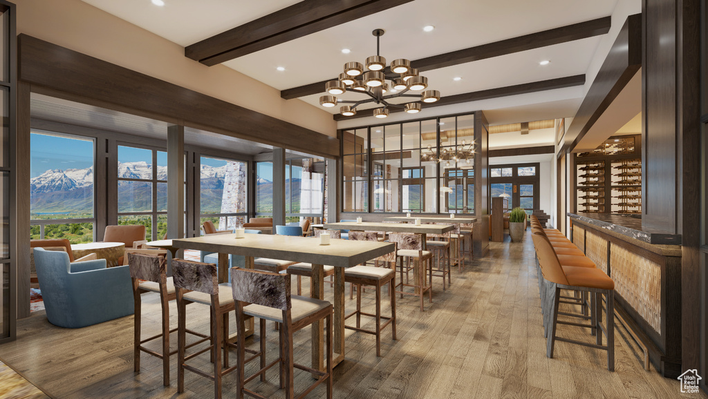 Dining area with beamed ceiling, light wood finished floors, a chandelier, a mountain view, and a community bar
