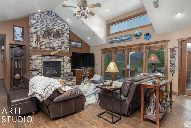 Living room with a ceiling fan, a fireplace, wood finished floors, high vaulted ceiling, and baseboards