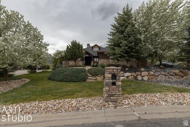 View of property hidden behind natural elements with a front yard
