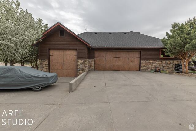 View of front of house featuring stone siding, a garage, and driveway