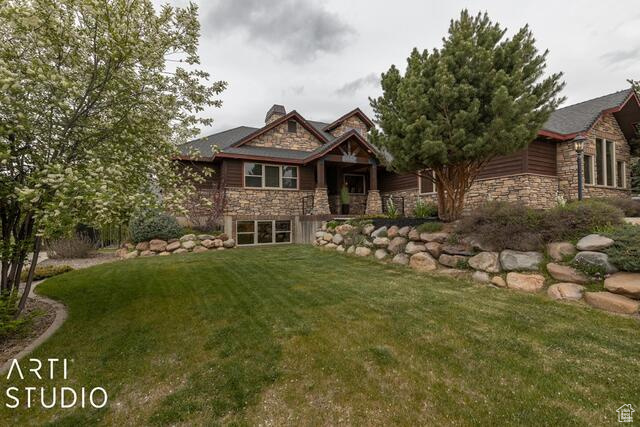Craftsman-style home featuring stone siding, a front yard, and a chimney