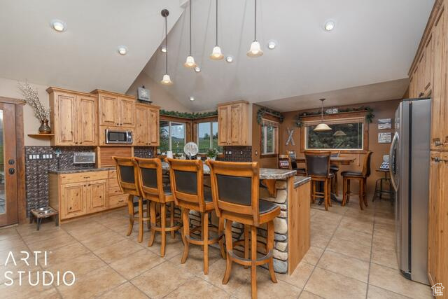 Kitchen with appliances with stainless steel finishes, light tile patterned floors, backsplash, lofted ceiling, and recessed lighting