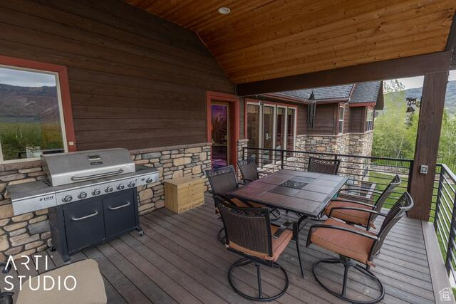 Wooden terrace with area for grilling, a mountain view, and outdoor dining area