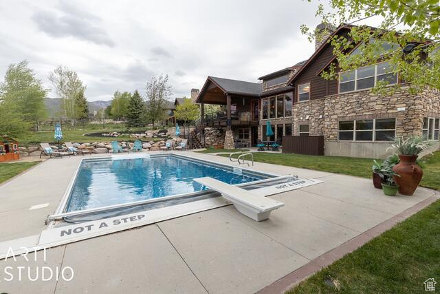 Outdoor pool featuring a patio, a diving board, and a lawn