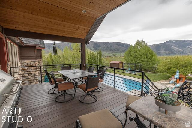 Deck with a mountain view, outdoor dining space, and area for grilling