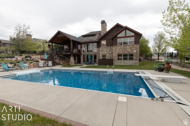 Swimming pool featuring a diving board, a patio area, and stairs