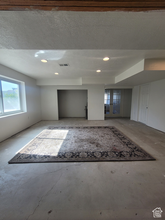 Unfurnished room with recessed lighting, concrete flooring, a textured ceiling, and french doors
