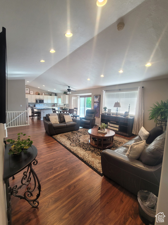 Living room with dark wood-type flooring, lofted ceiling, ceiling fan, and recessed lighting