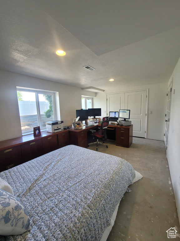 Bedroom with unfinished concrete floors, an office area, and recessed lighting