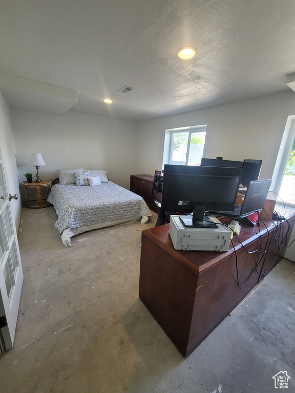 Bedroom with concrete flooring, a desk, multiple windows, a textured ceiling, and recessed lighting