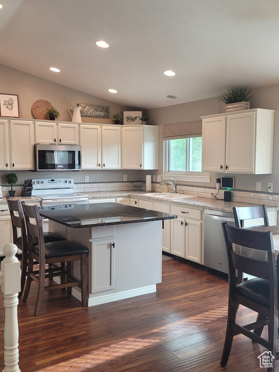 Kitchen featuring stainless steel appliances, a sink, white cabinetry, recessed lighting, and a center island