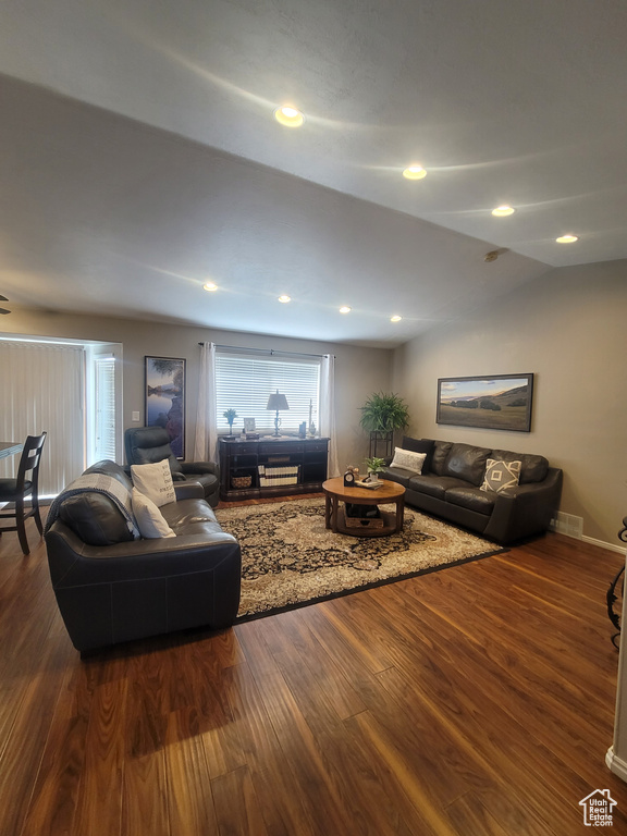 Living room with dark wood-style flooring, lofted ceiling, and recessed lighting