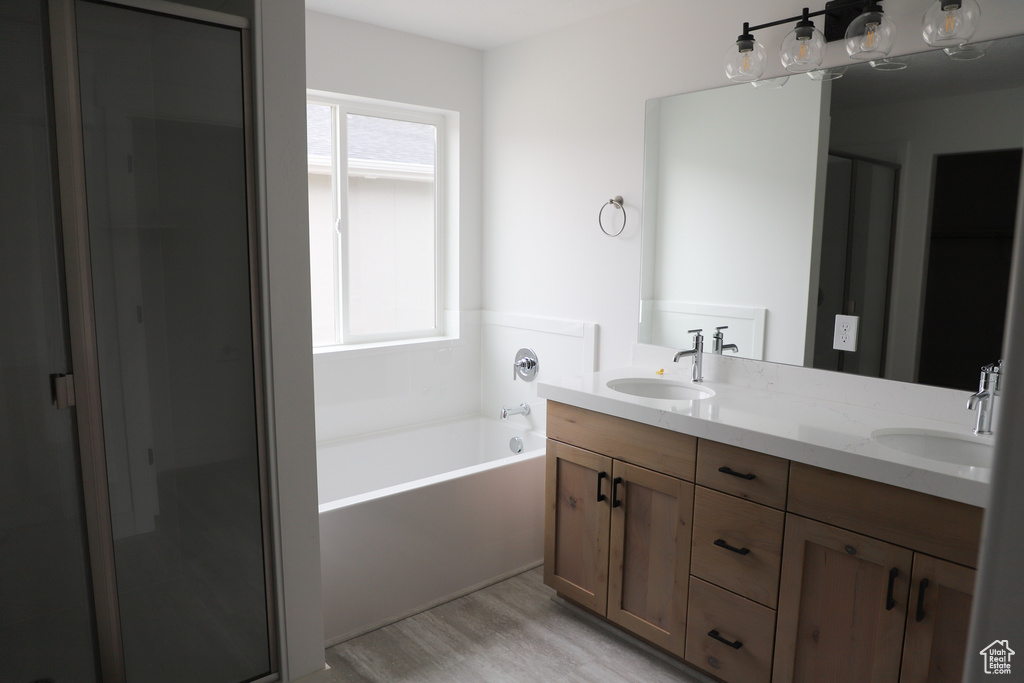 Bathroom with double vanity, a garden tub, and wood finished floors
