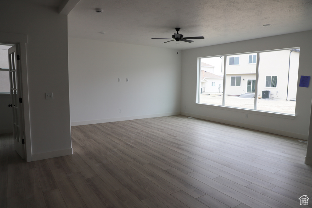 Unfurnished room with ceiling fan, wood finished floors, and baseboards