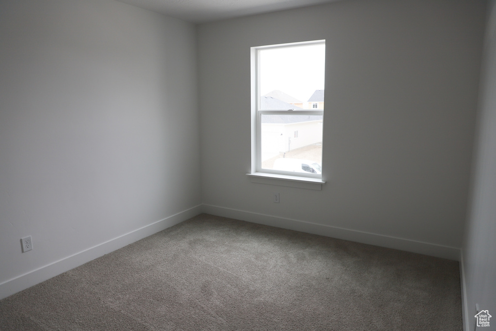 Carpeted empty room featuring baseboards