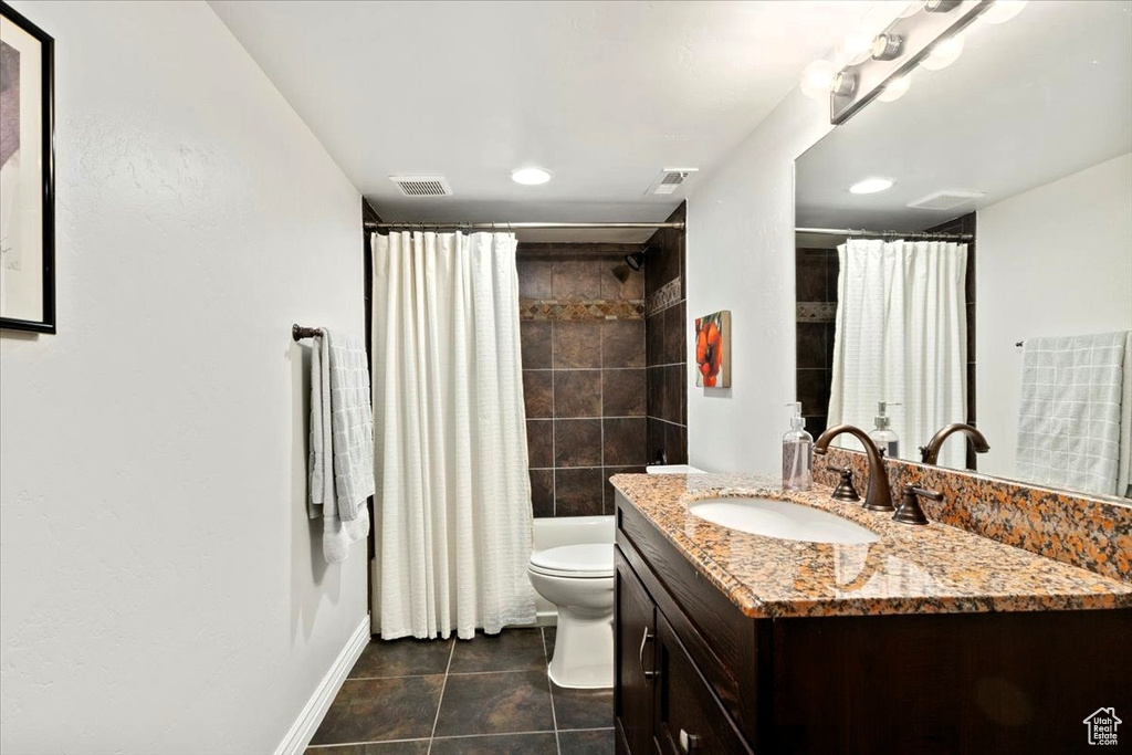 Full bathroom featuring vanity, toilet, baseboards, tile patterned flooring, and shower / bath combo with shower curtain