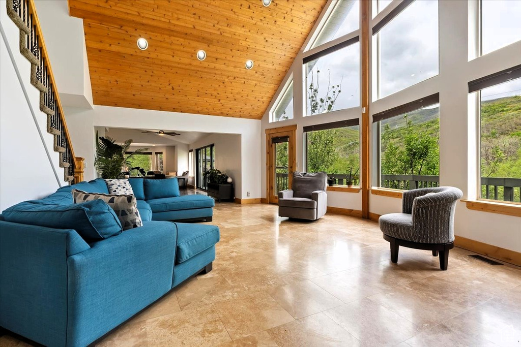 Living room with high vaulted ceiling, healthy amount of natural light, baseboards, stairs, and wood ceiling