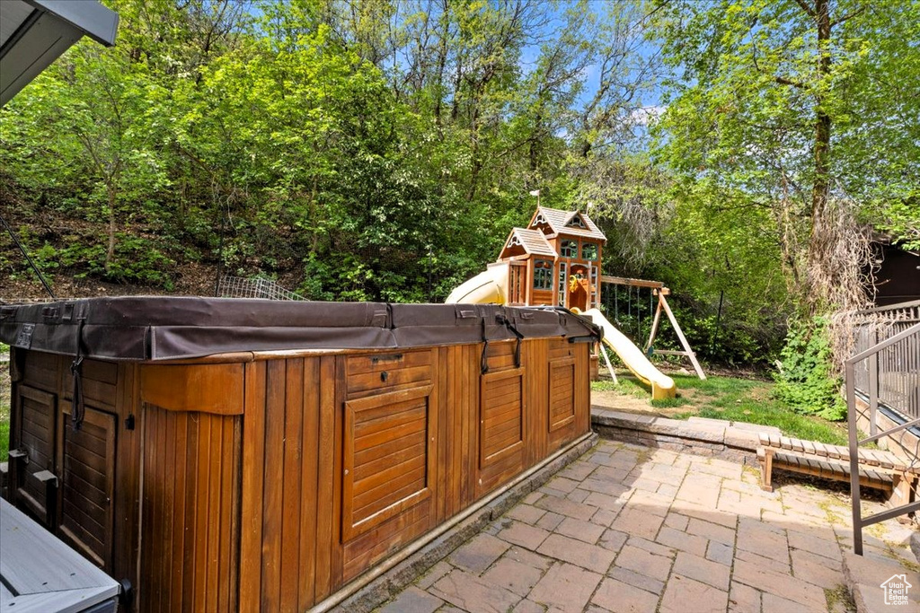 View of patio / terrace with a hot tub and a playground