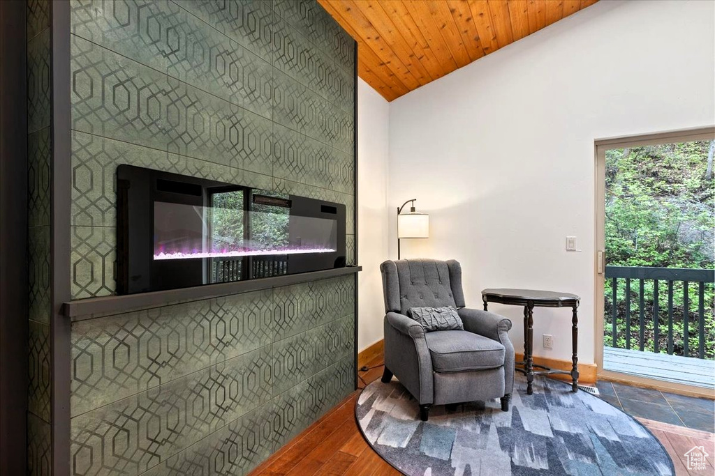 Living area with baseboards, a glass covered fireplace, and high vaulted ceiling