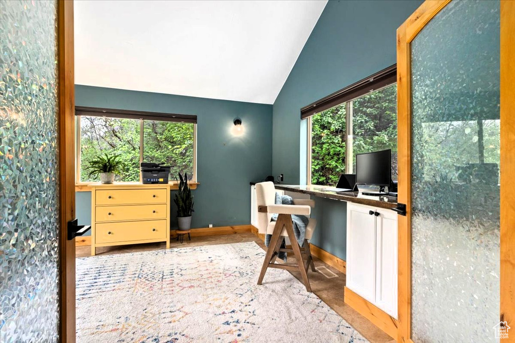 Home office with lofted ceiling, plenty of natural light, and baseboards