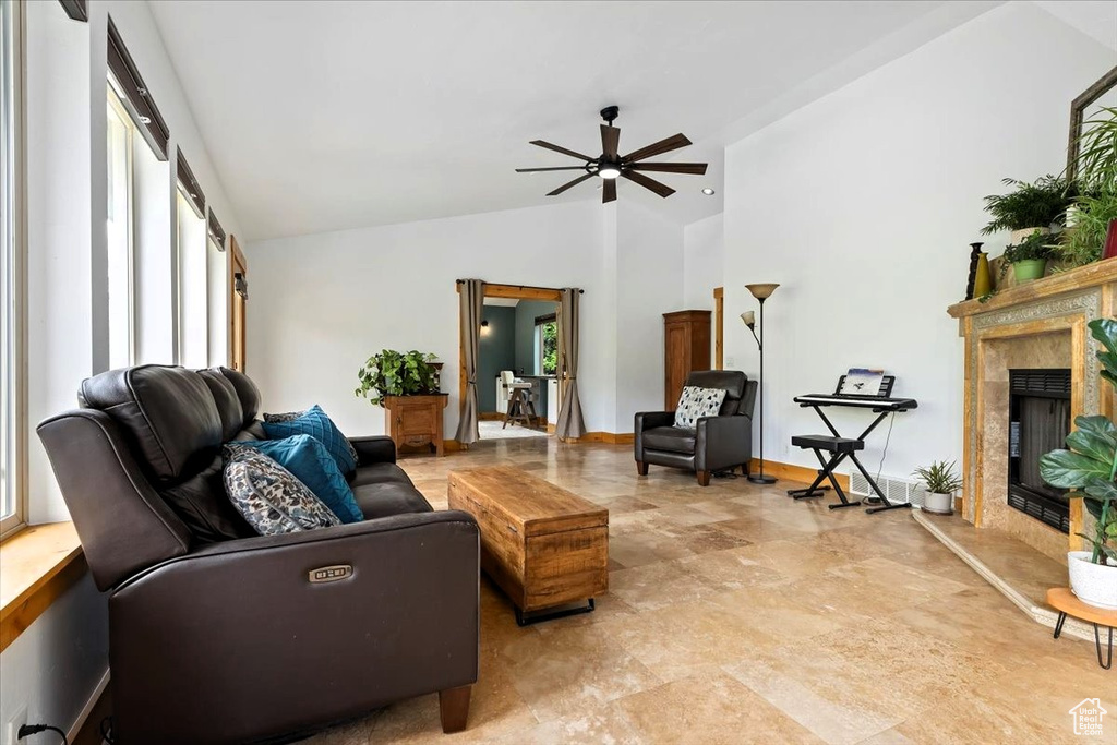 Living area with healthy amount of natural light, a ceiling fan, a fireplace, and high vaulted ceiling