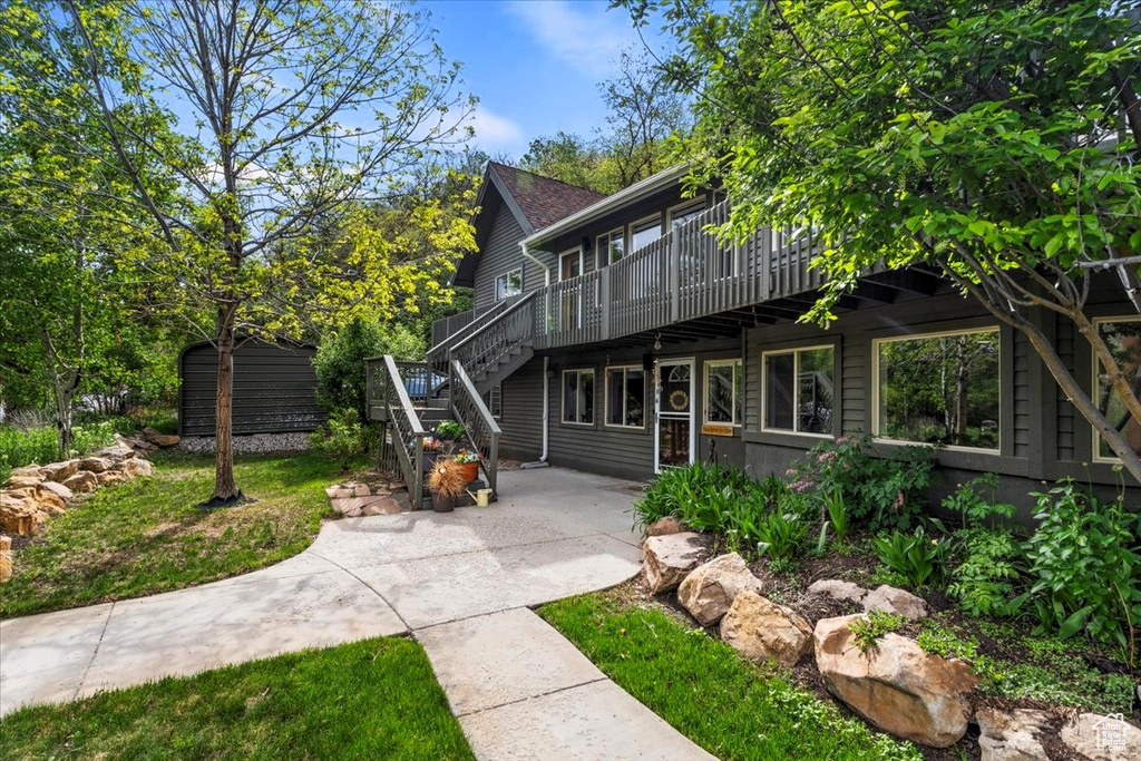 View of front of home with a wooden deck, stairway, and a patio area