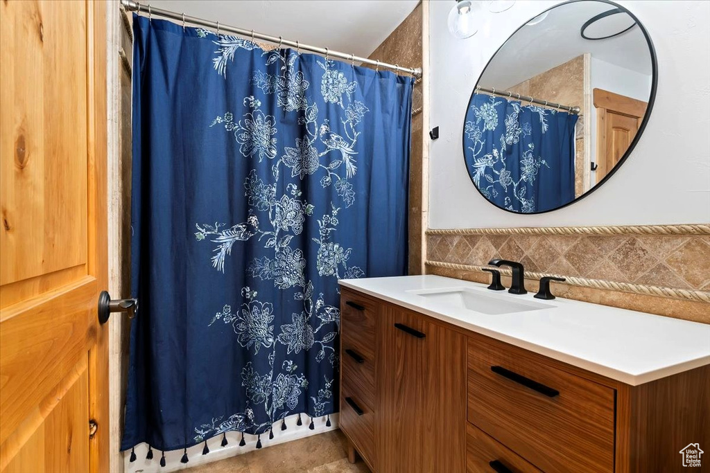 Bathroom featuring vanity, a shower with shower curtain, and tasteful backsplash