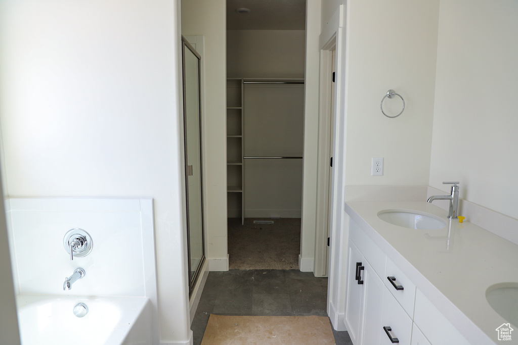 Full bath with a bath, double vanity, a stall shower, and a walk in closet