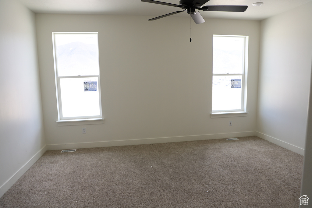 Empty room with ceiling fan, carpet floors, and baseboards