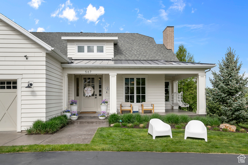 View of front of home with a standing seam roof, a porch, roof with shingles, and metal roof
