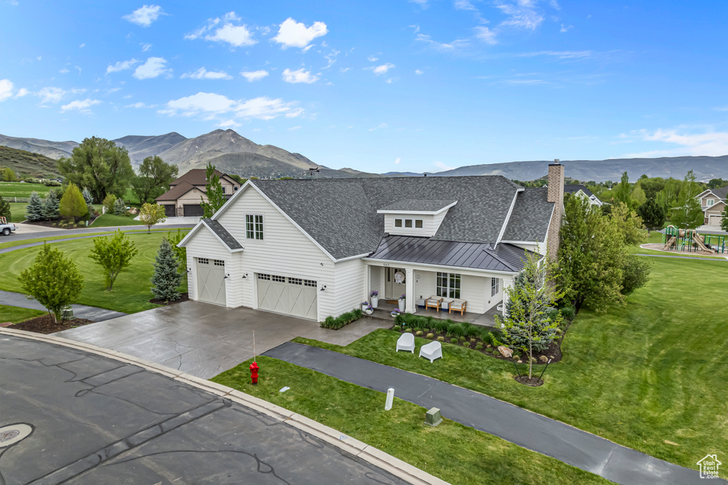 View of front of house with a porch, a standing seam roof, a mountain view, a shingled roof, and concrete driveway