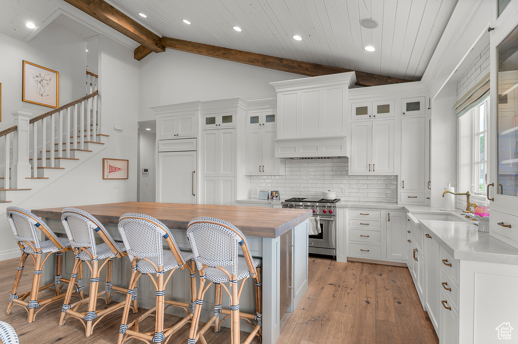 Kitchen with premium range, a sink, wooden counters, light wood-type flooring, and backsplash