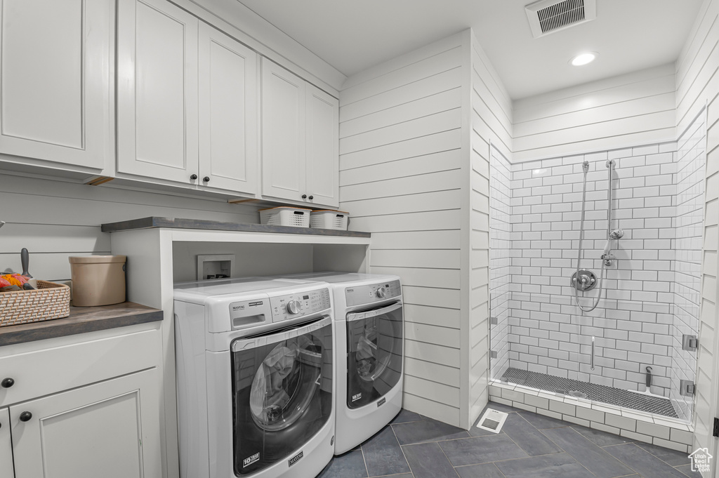 Laundry area with washing machine and clothes dryer, dark tile patterned flooring, cabinet space, and recessed lighting