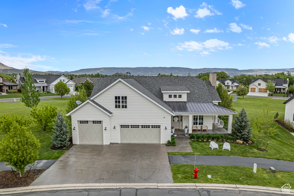 Modern inspired farmhouse featuring a porch, a mountain view, a front yard, and driveway