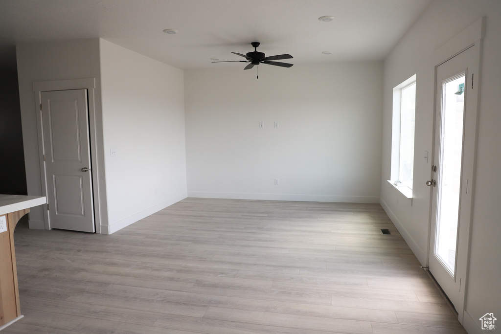 Empty room featuring a ceiling fan, light wood-style floors, and baseboards