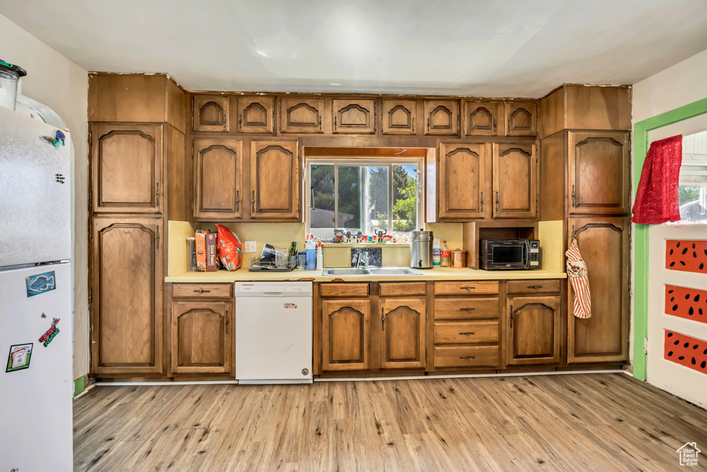 Kitchen featuring white appliances and brown cabinetry
