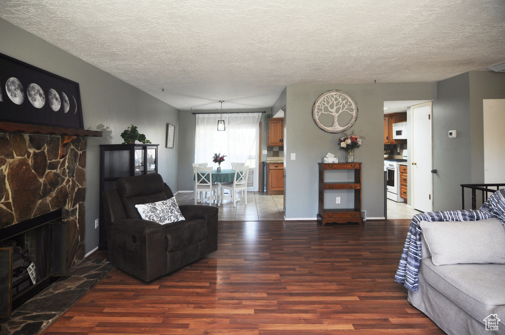 Living room featuring wood finished floors, a textured ceiling, a fireplace, and baseboards