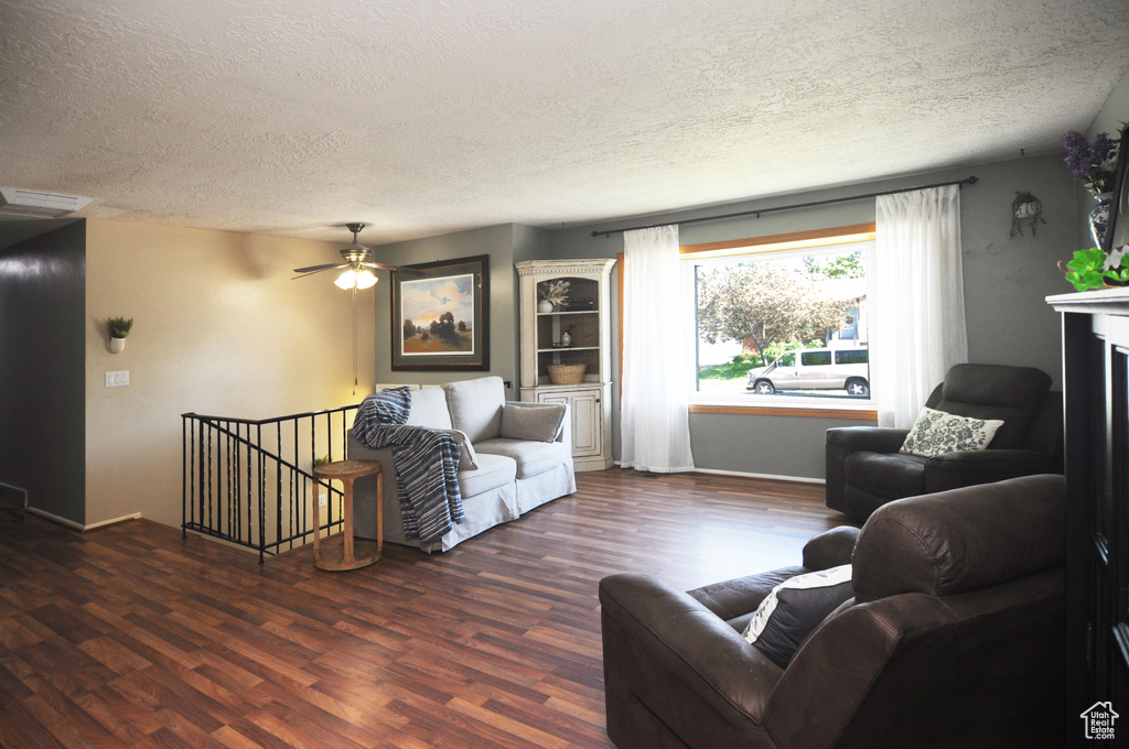 Living area featuring a textured ceiling, wood finished floors, ceiling fan, and baseboards