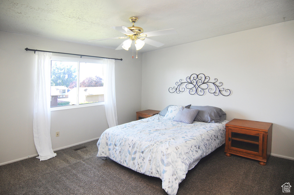 Bedroom with dark carpet, baseboards, and a ceiling fan