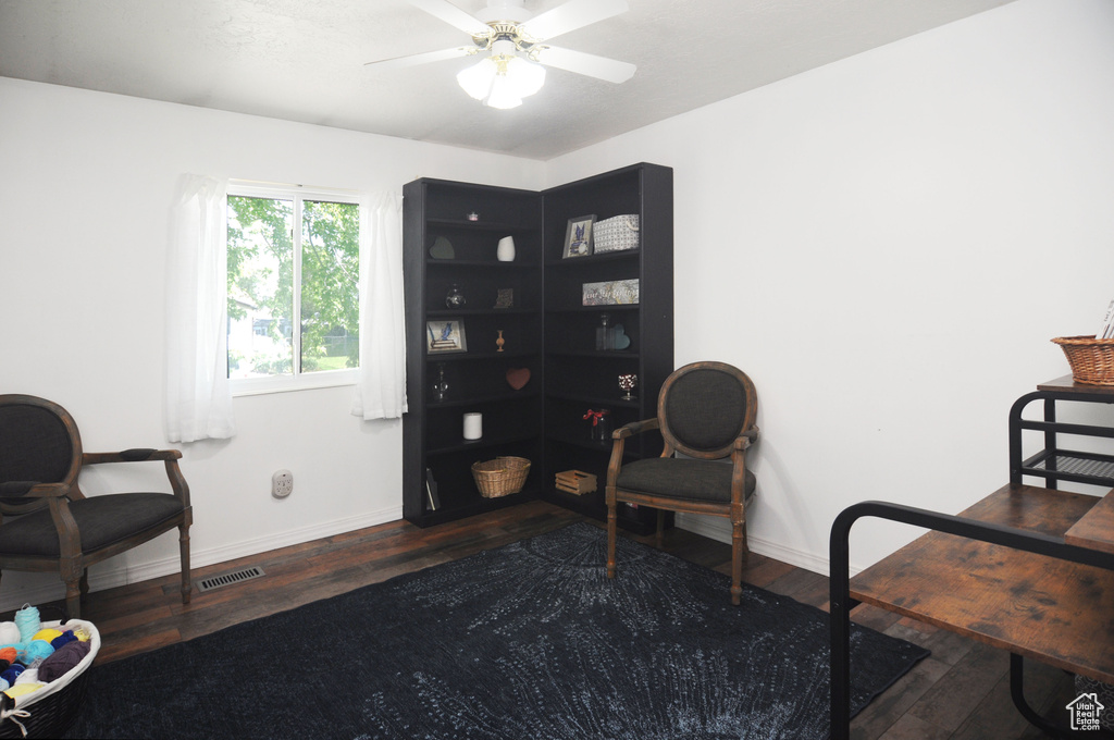 Living area featuring wood finished floors, baseboards, and ceiling fan