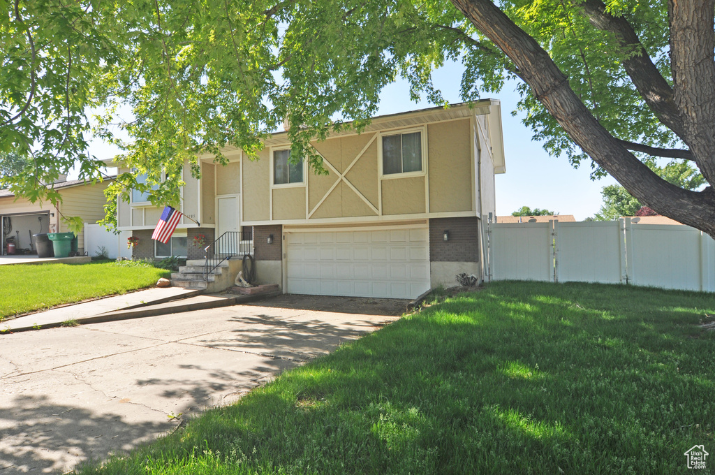 View of front of home featuring driveway, a garage, a gate, brick siding, and stucco siding