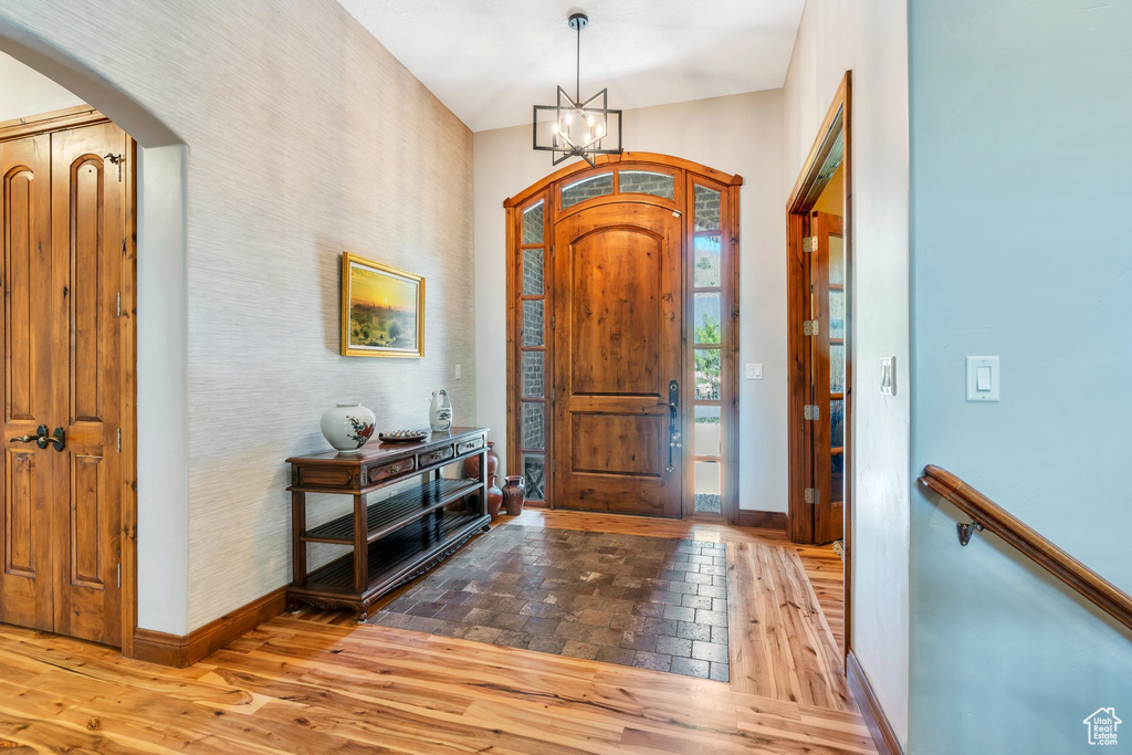 Entrance foyer with baseboards, arched walkways, a chandelier, and wood finished floors