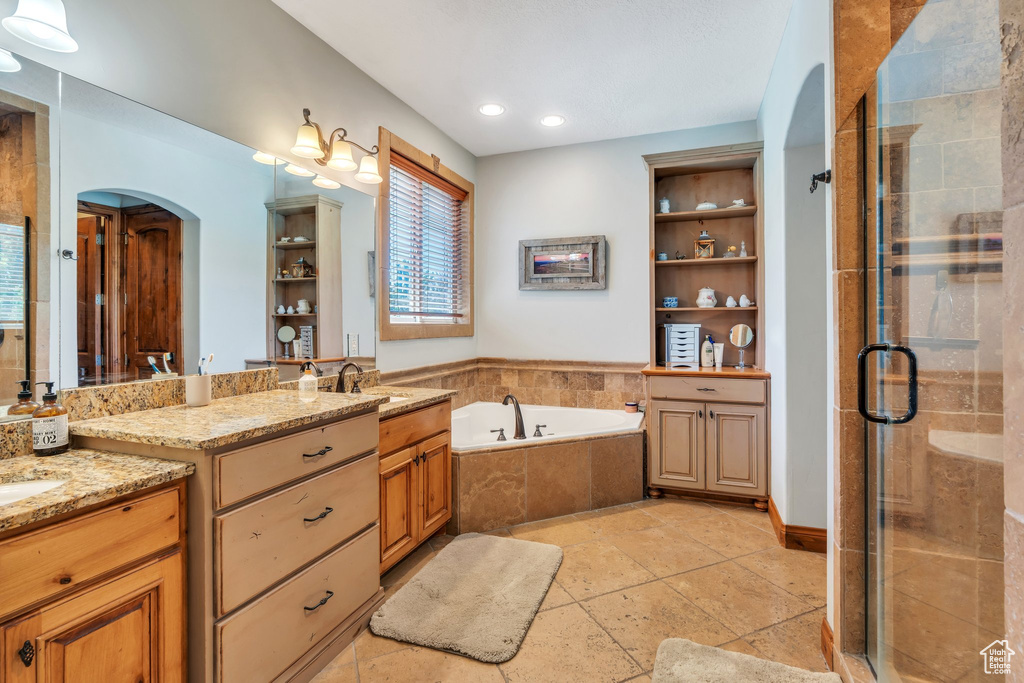 Bathroom with two vanities, a shower stall, a bath, and recessed lighting